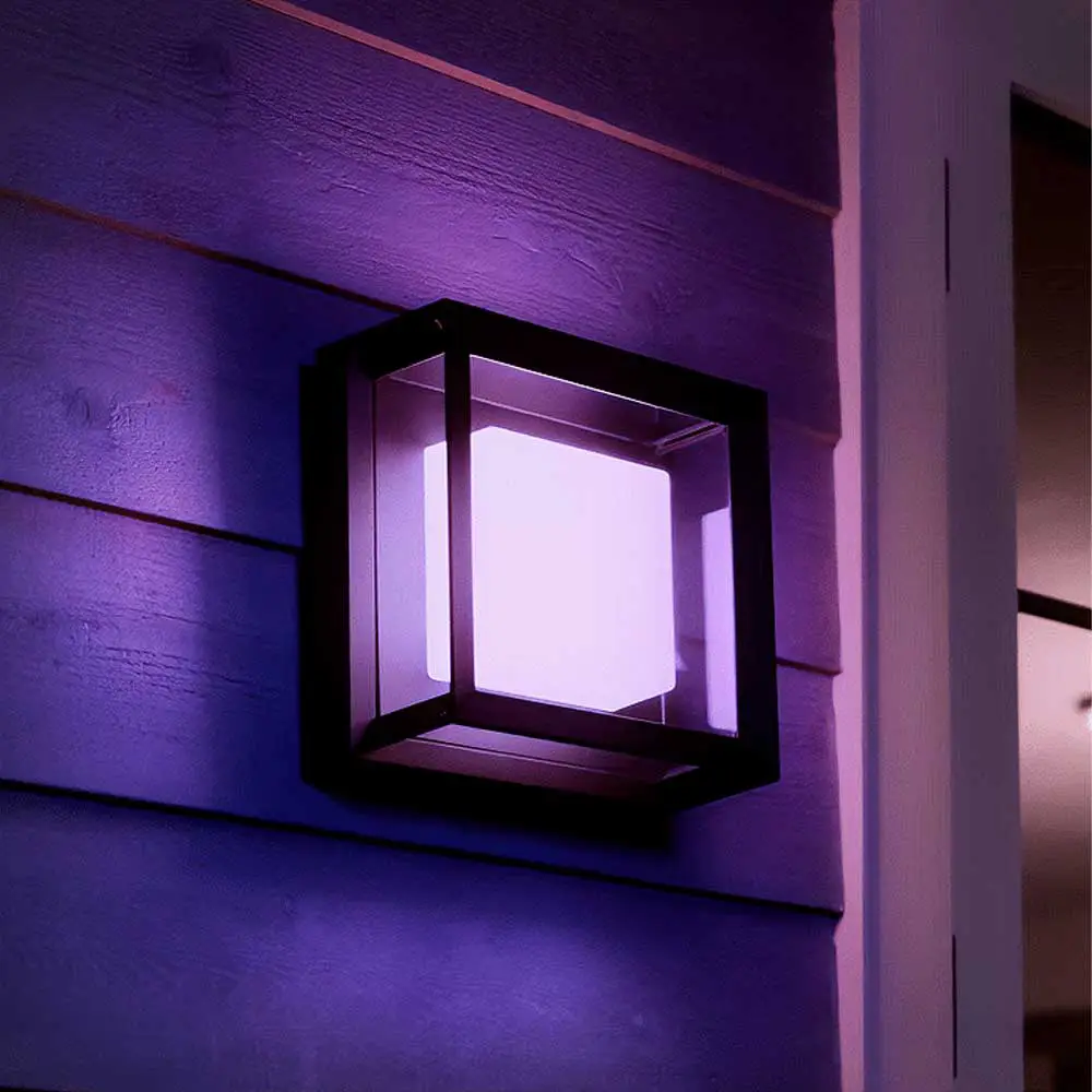 Aplique exterior Econic Philips Hue negro iluminando fachada con luz rosa.