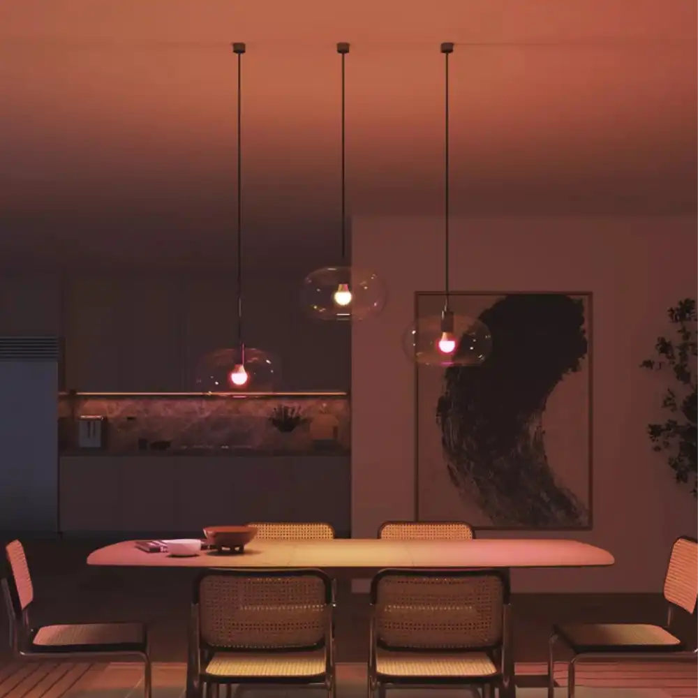 Ambiente de comedor iluminado con bombillas Philips Hue White & Color A60 E27 8W en tonos cálidos.
