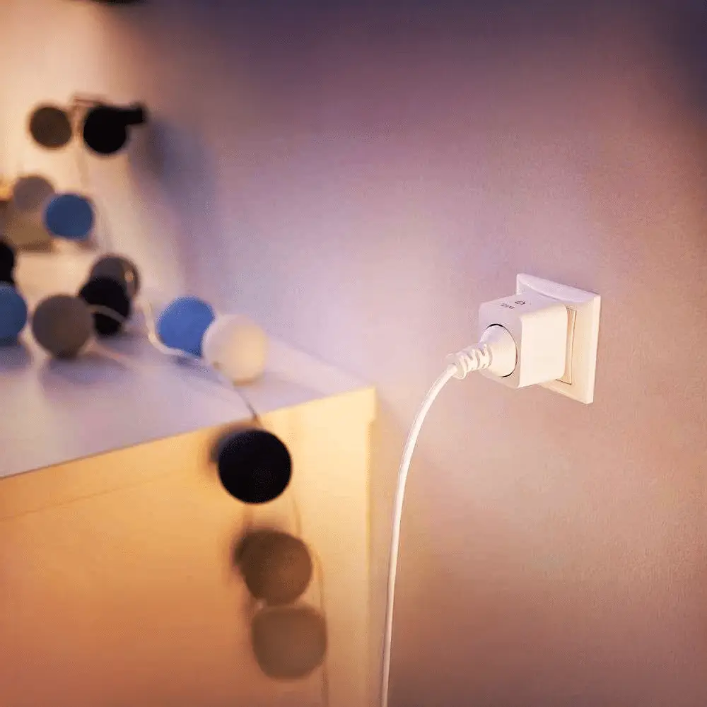 Enchufe inteligente WiZ blanco conectado en pared con iluminación ambiental.