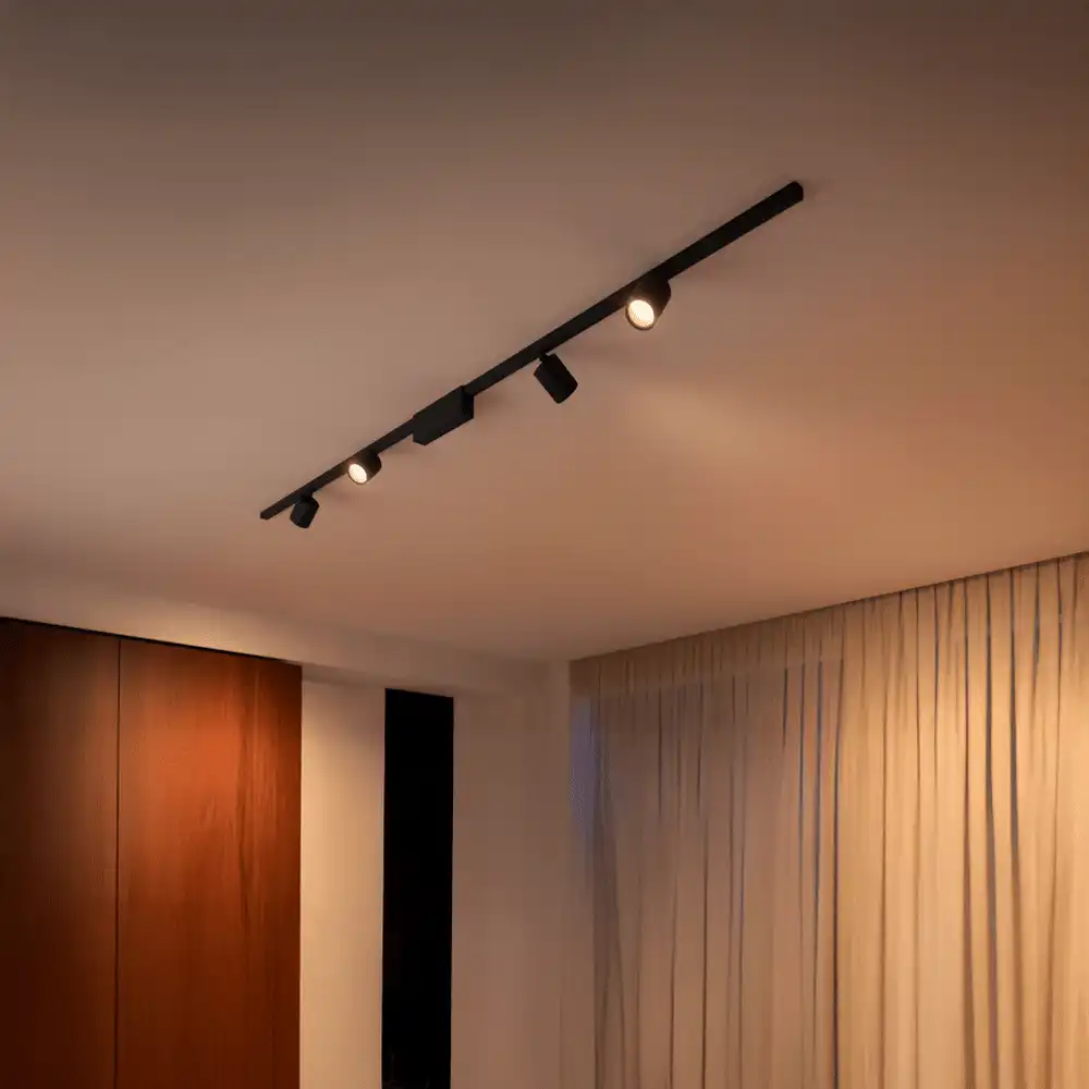 Foco de carril cilíndrico Perifo Philips Hue negro White and Color instalado en techo con iluminación cálida.