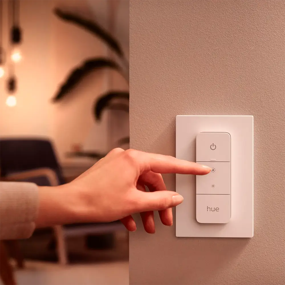 Interruptor Dimmer Switch Philips Hue instalado en pared siendo pulsado.