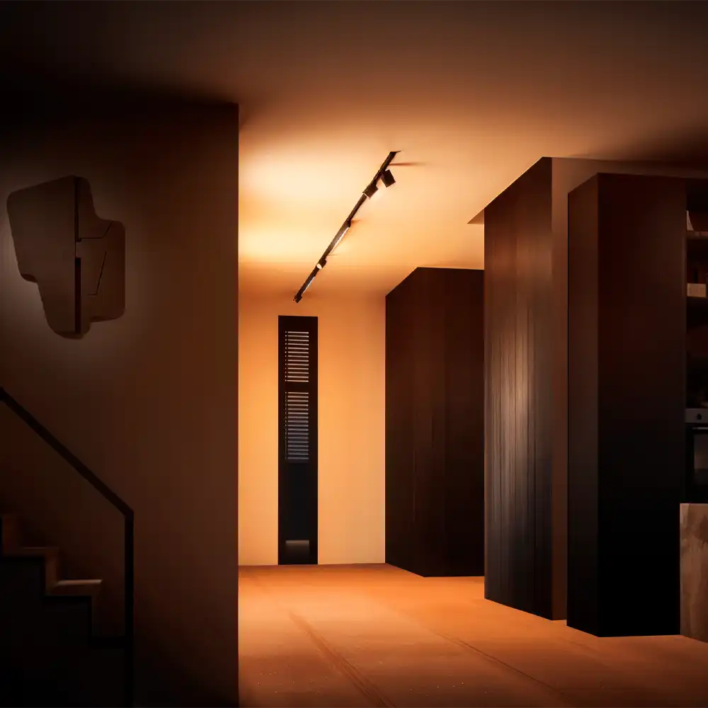 Kit Perifo Philips Hue negro con 3 focos y barra de luz White and Color instalado en pasillo moderno.