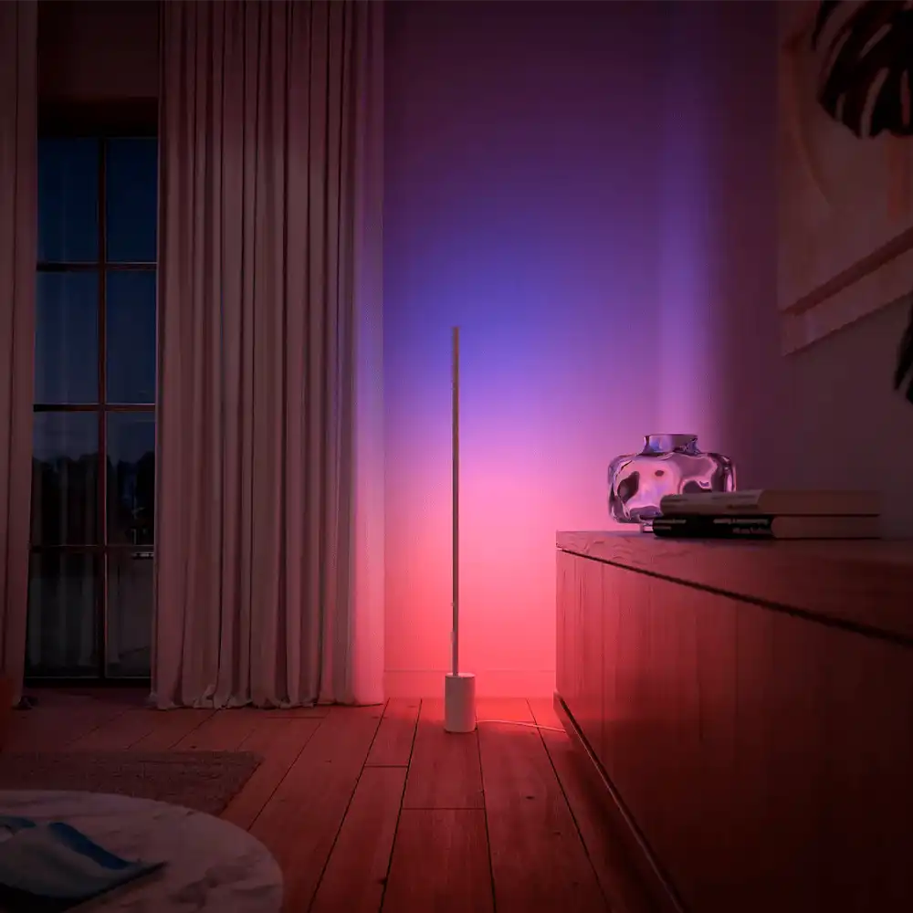 Lámpara de suelo Gradient Signe Philips Hue blanca proyectando luz ambiental roja y azul en salón moderno
