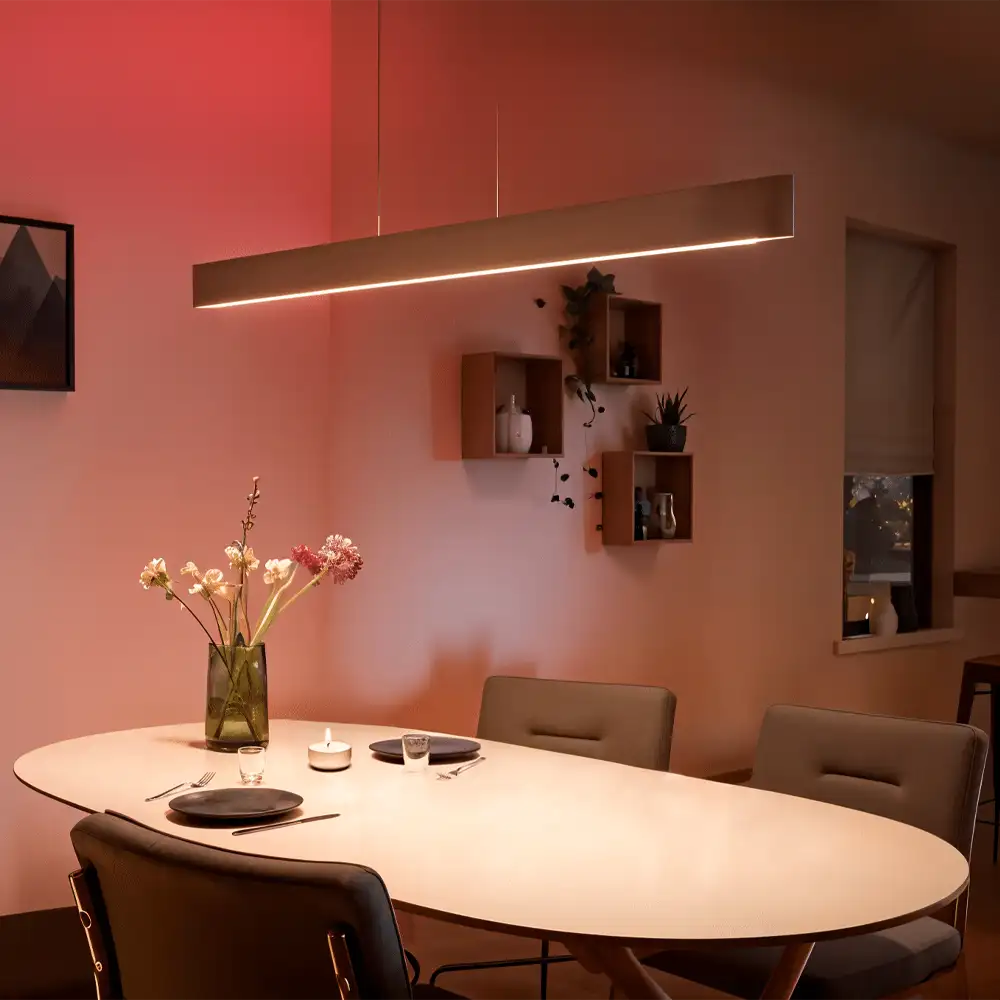 Lámpara de techo Ensis Philips Hue blanca instalada sobre mesa de comedor con iluminación ambiental cálida