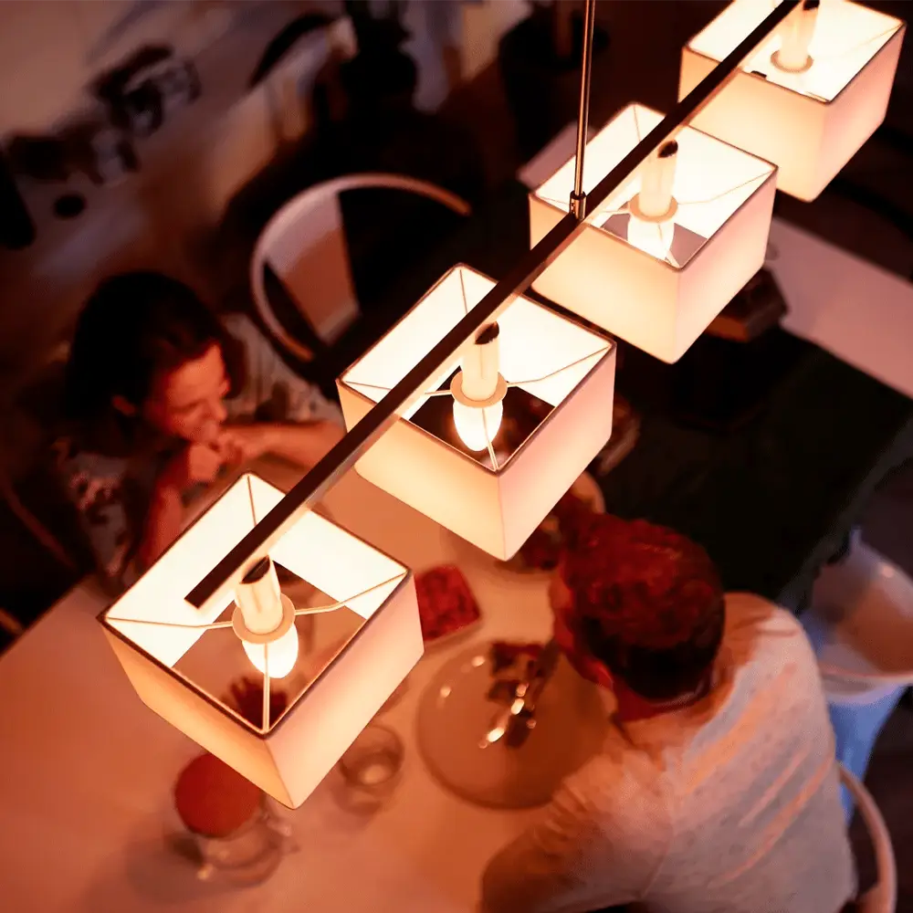 Pack 2 bombillas vela Philips Hue White 5.5W E14 instaladas en lámpara de techo con luz cálida.